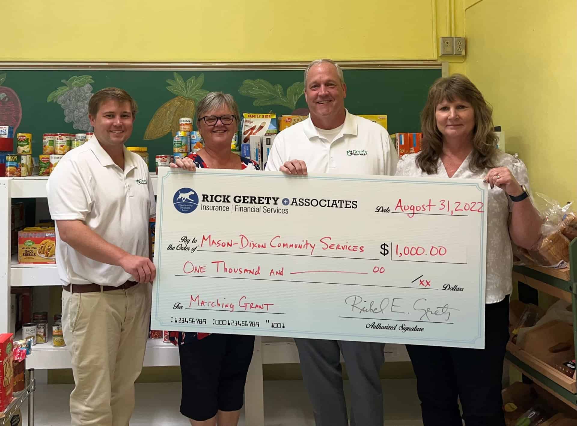 Four people holding oversized $1,000 donation check