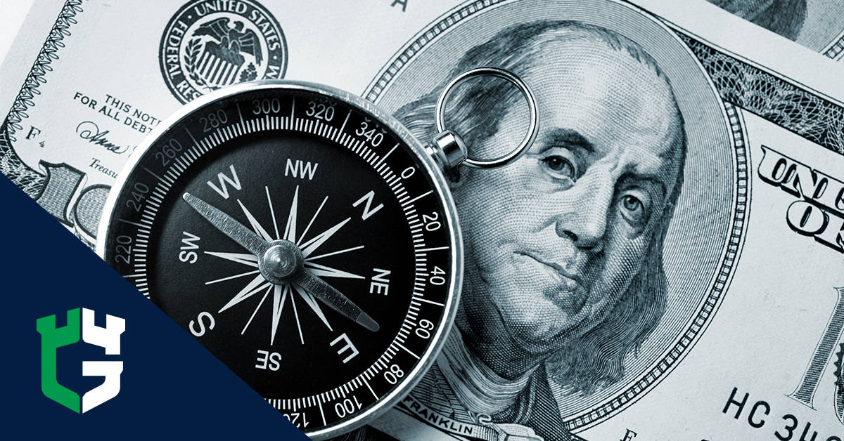Compass resting on a US $100 bill showing Benjamin Franklin