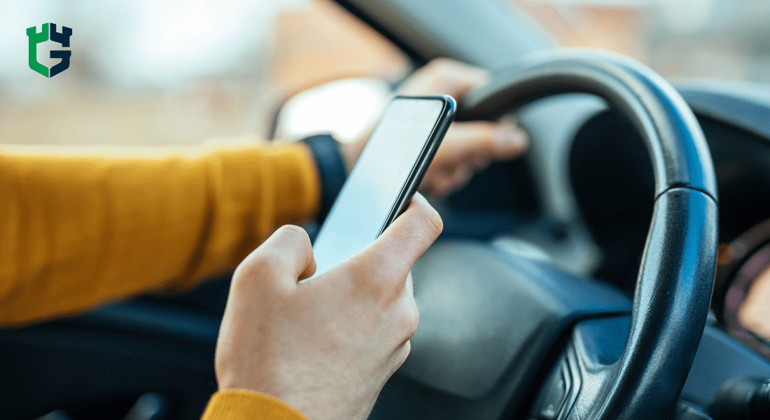Driver using smartphone with one hand on the steering wheel