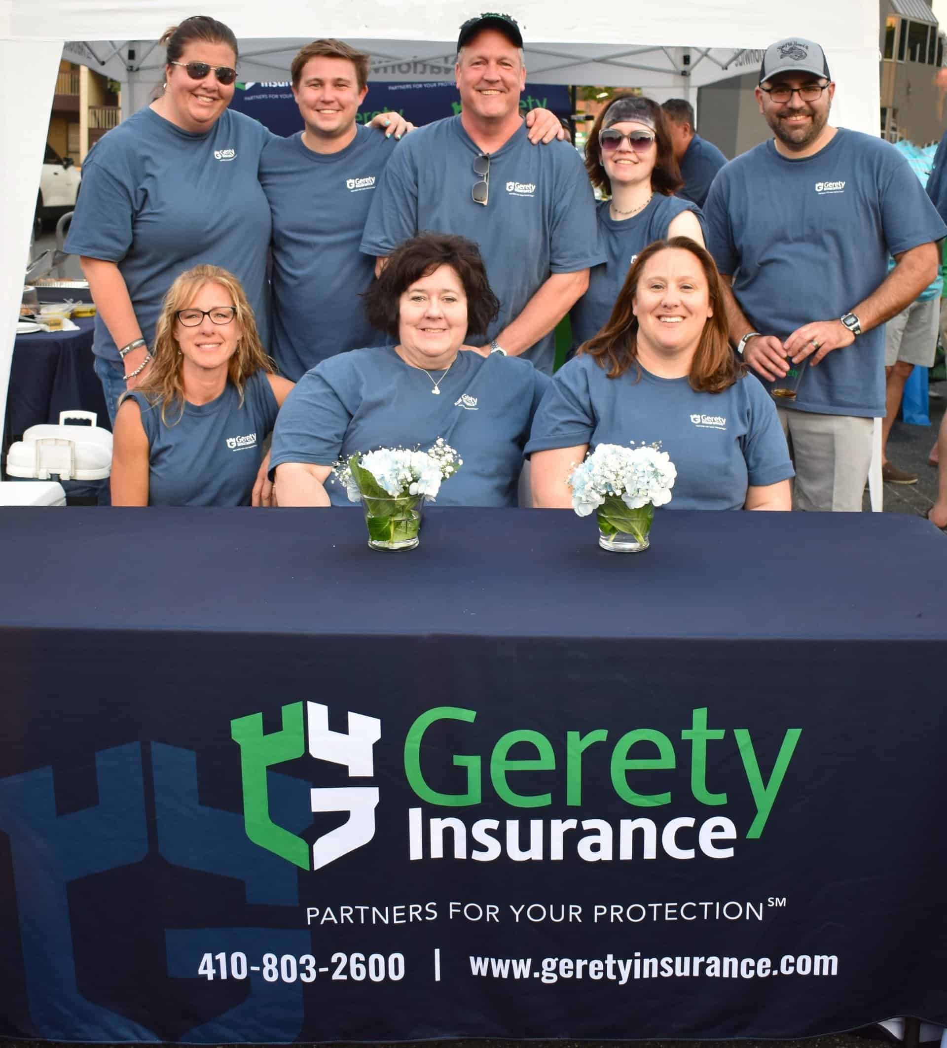 Gerety Insurance team in blue shirts smiling behind branded table.