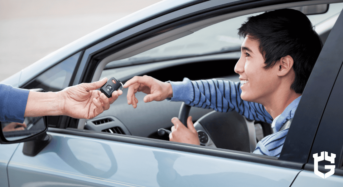 Smiling teen driver in car reaches for keys handed through window