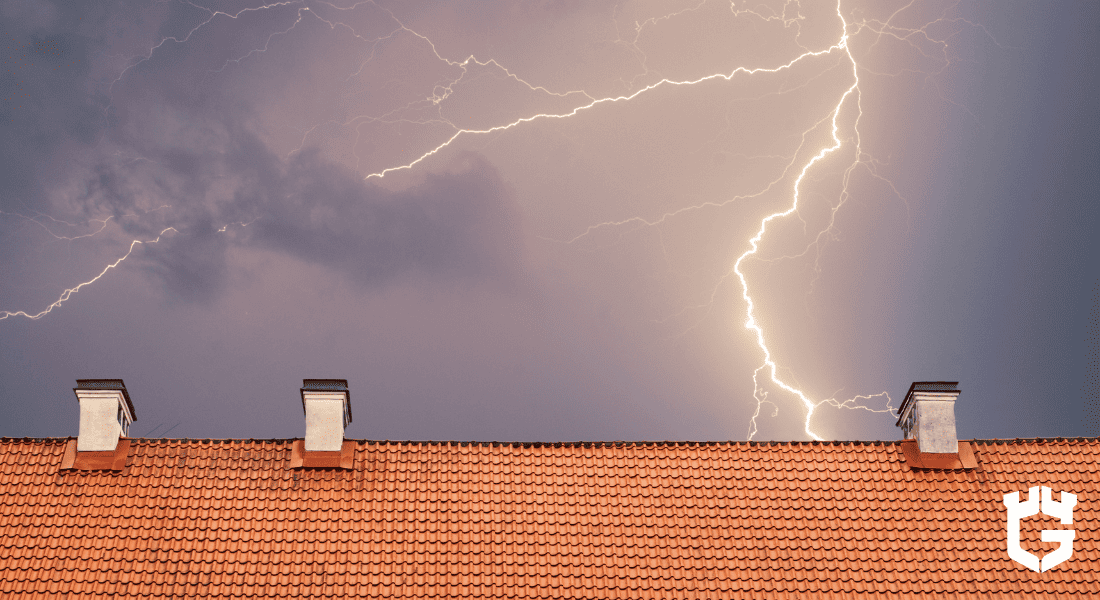 Lightning bolt over red-tiled roof with three chimneys.
