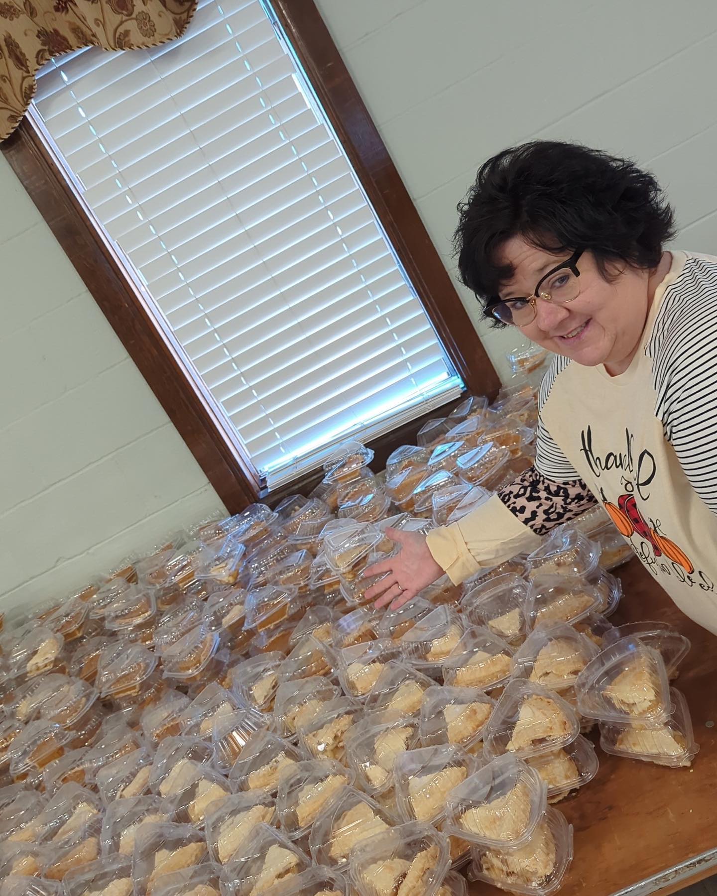 Woman gesturing at table full of plastic-packaged pie slices