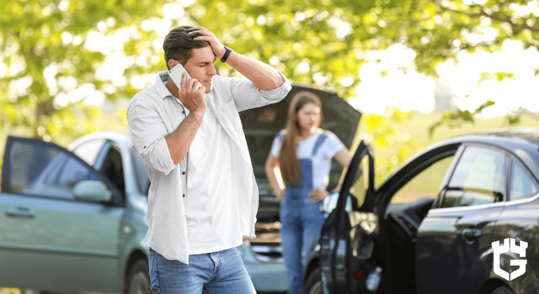 Man on phone beside two broken-down cars, woman standing by open hood