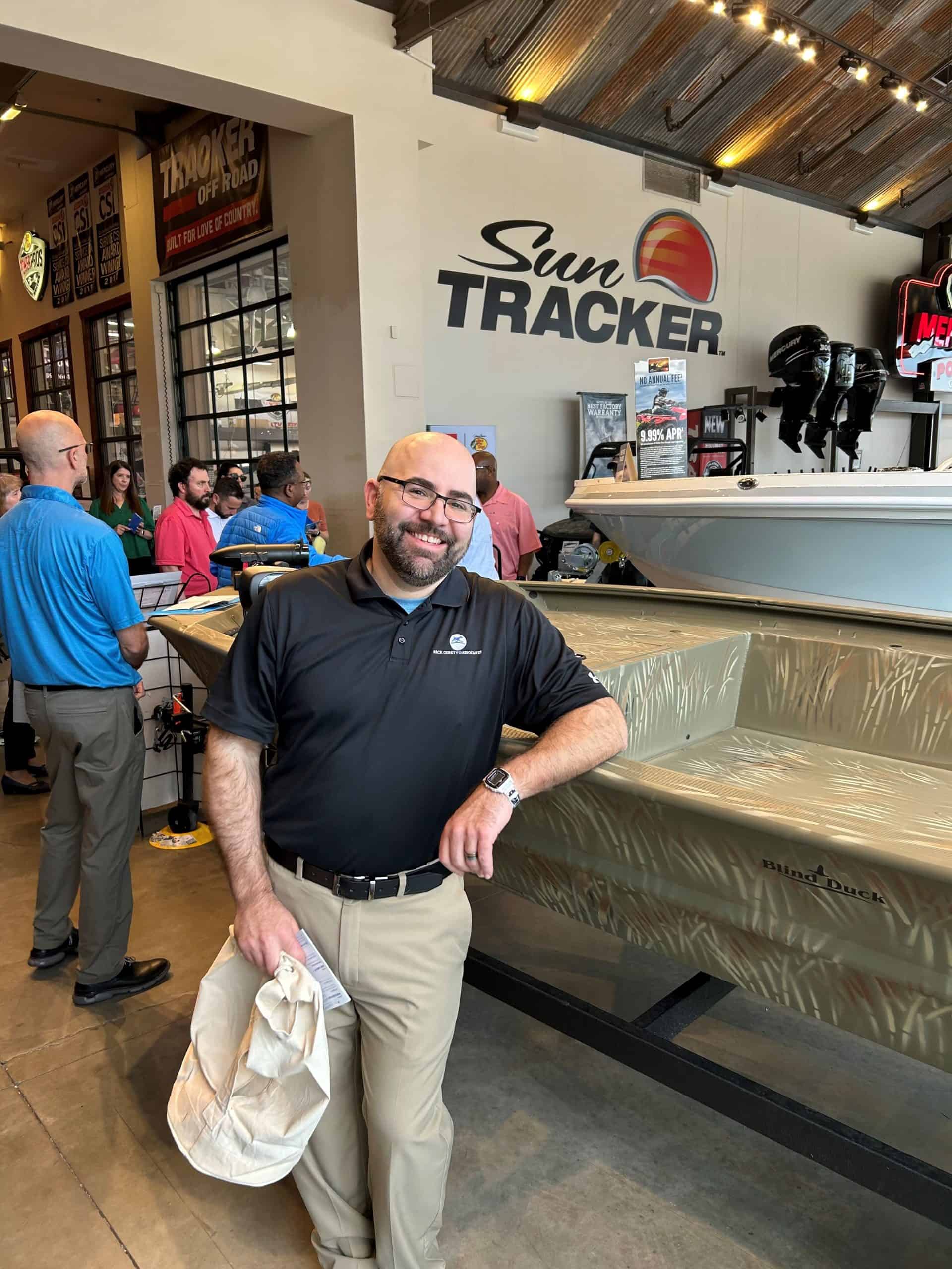 Smiling man in black polo leaning on boat