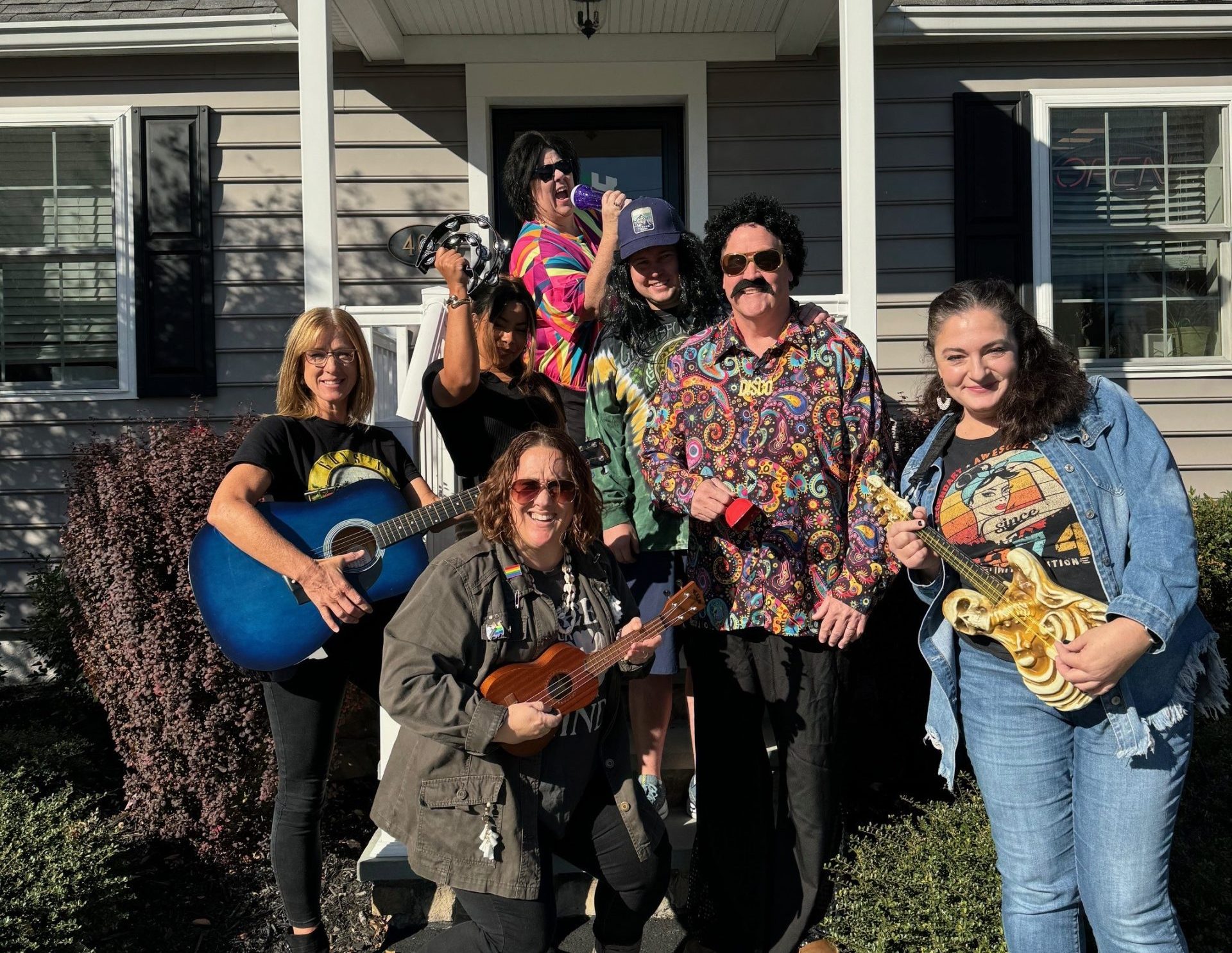 Gerety Insurance staff in retro costumes holding guitars and tambourine on porch