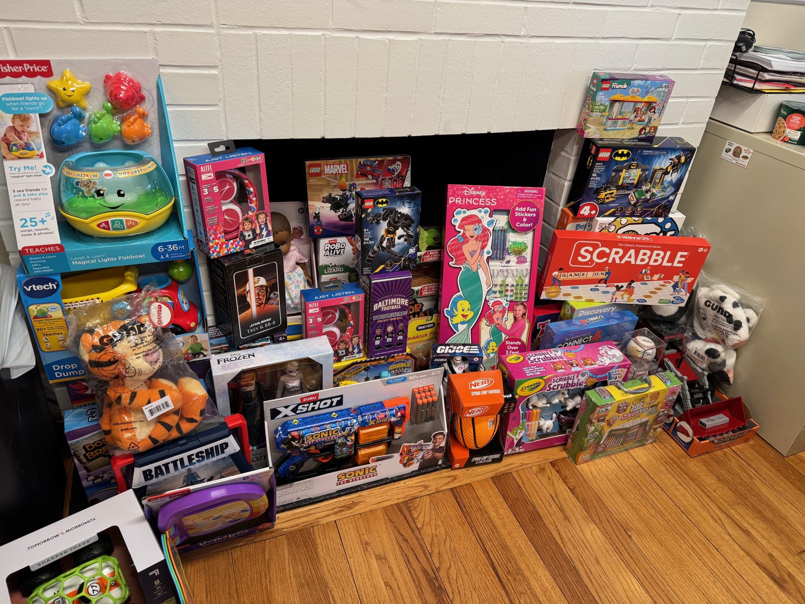 Stack of boxed toys and games in front of a white brick fireplace