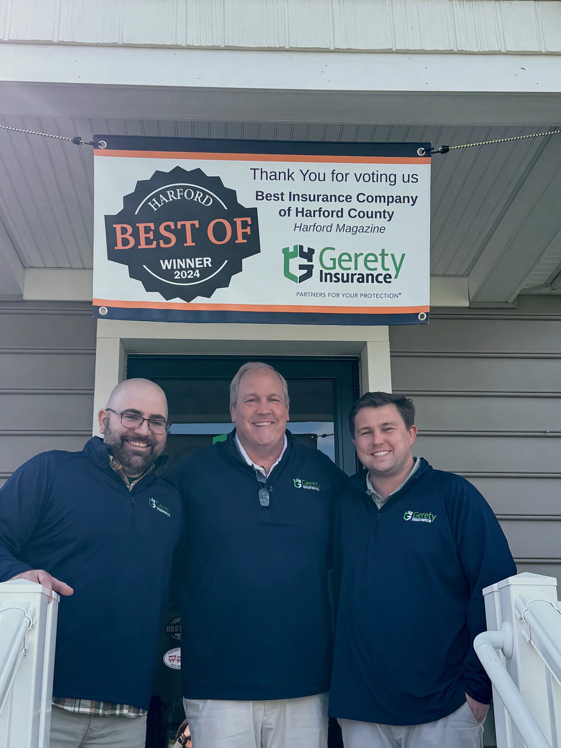 Three men smiling under 'Best of Harford' Gerety Insurance banner