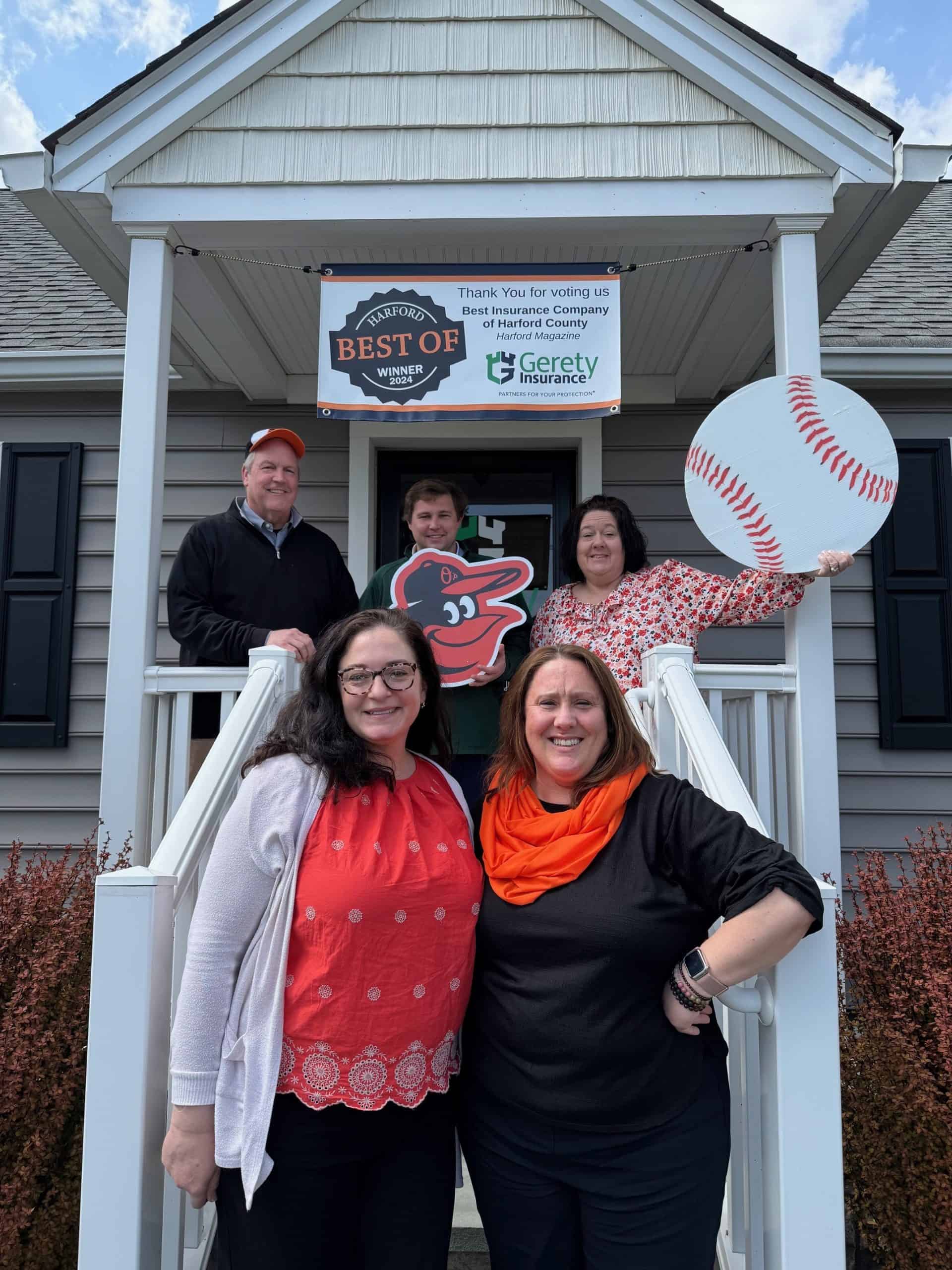 Five people on porch under Best of Harford 2024 banner with baseball cutouts