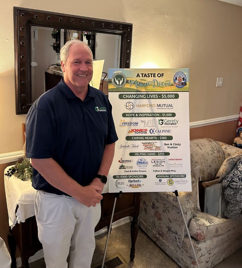Rick Gerety in navy polo beside event sponsor poster
