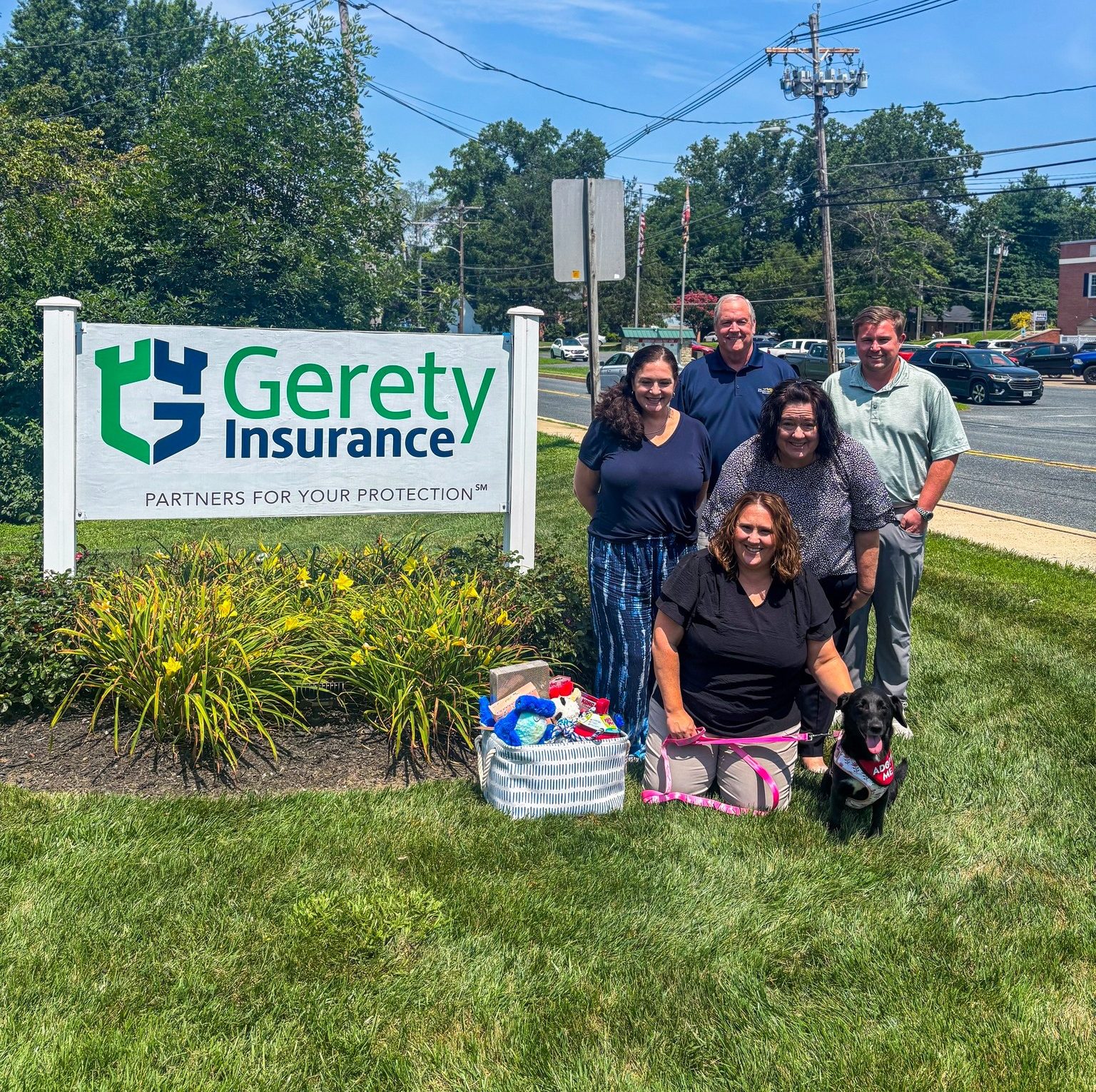 Five employees by Gerety Insurance sign with dog
