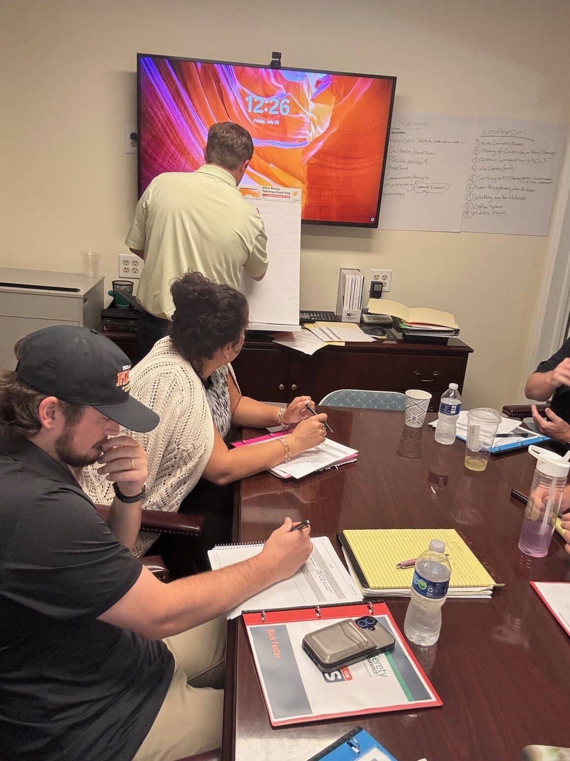 Team meeting with a man writing on a flip chart.