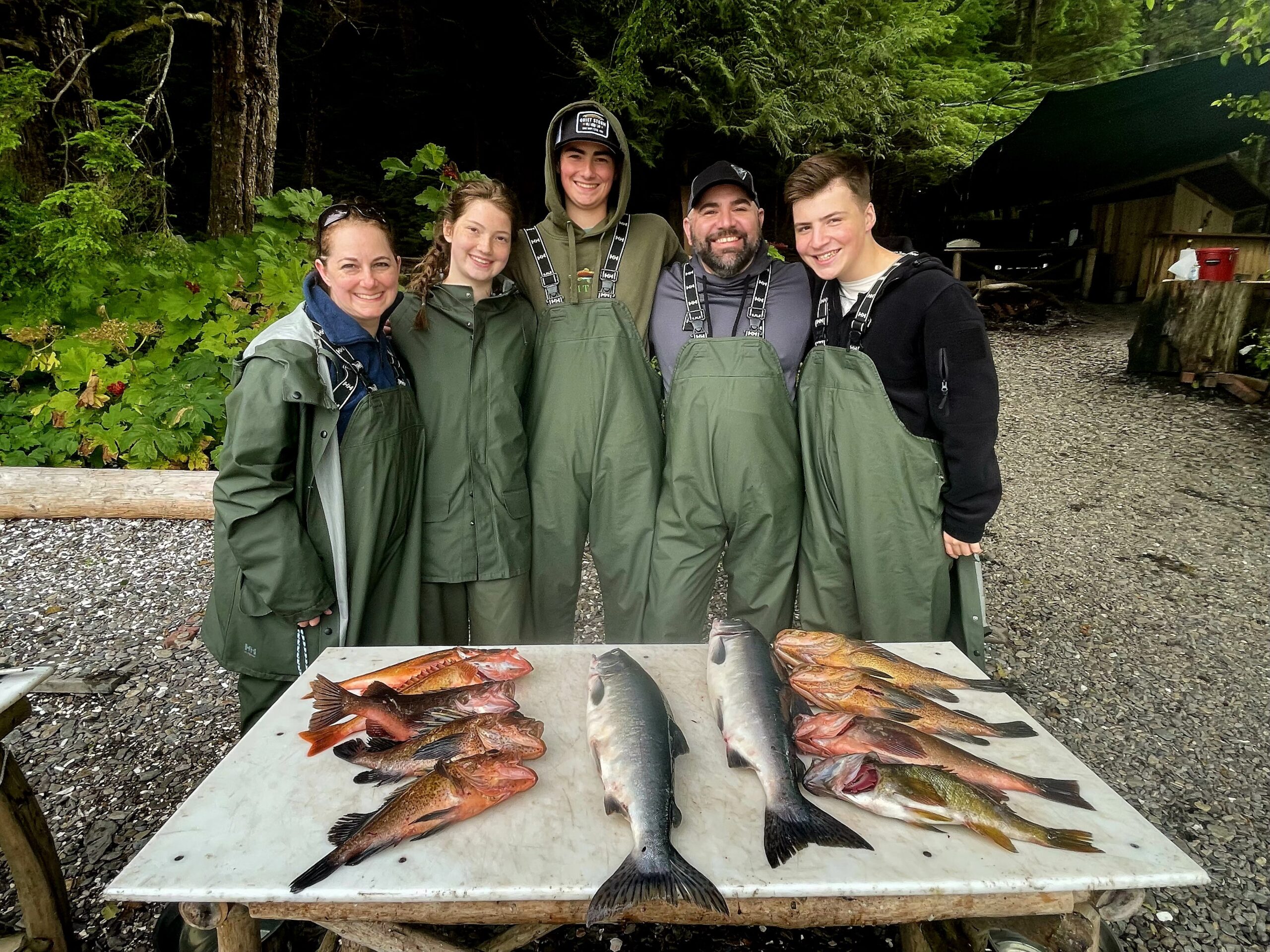 Chris Baur standing with a group wearing fishing waders behind a table of freshly caught fish.