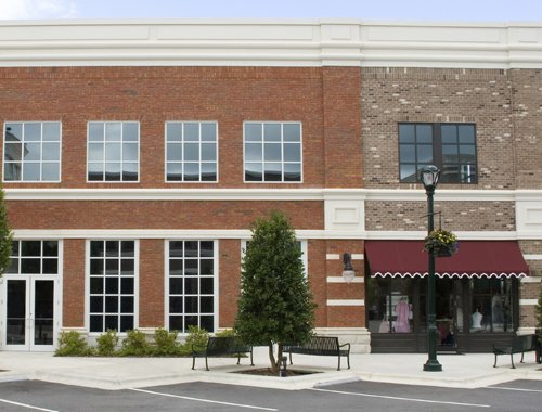 Two-story brick storefronts with large windows, awning, benches, lamppost.