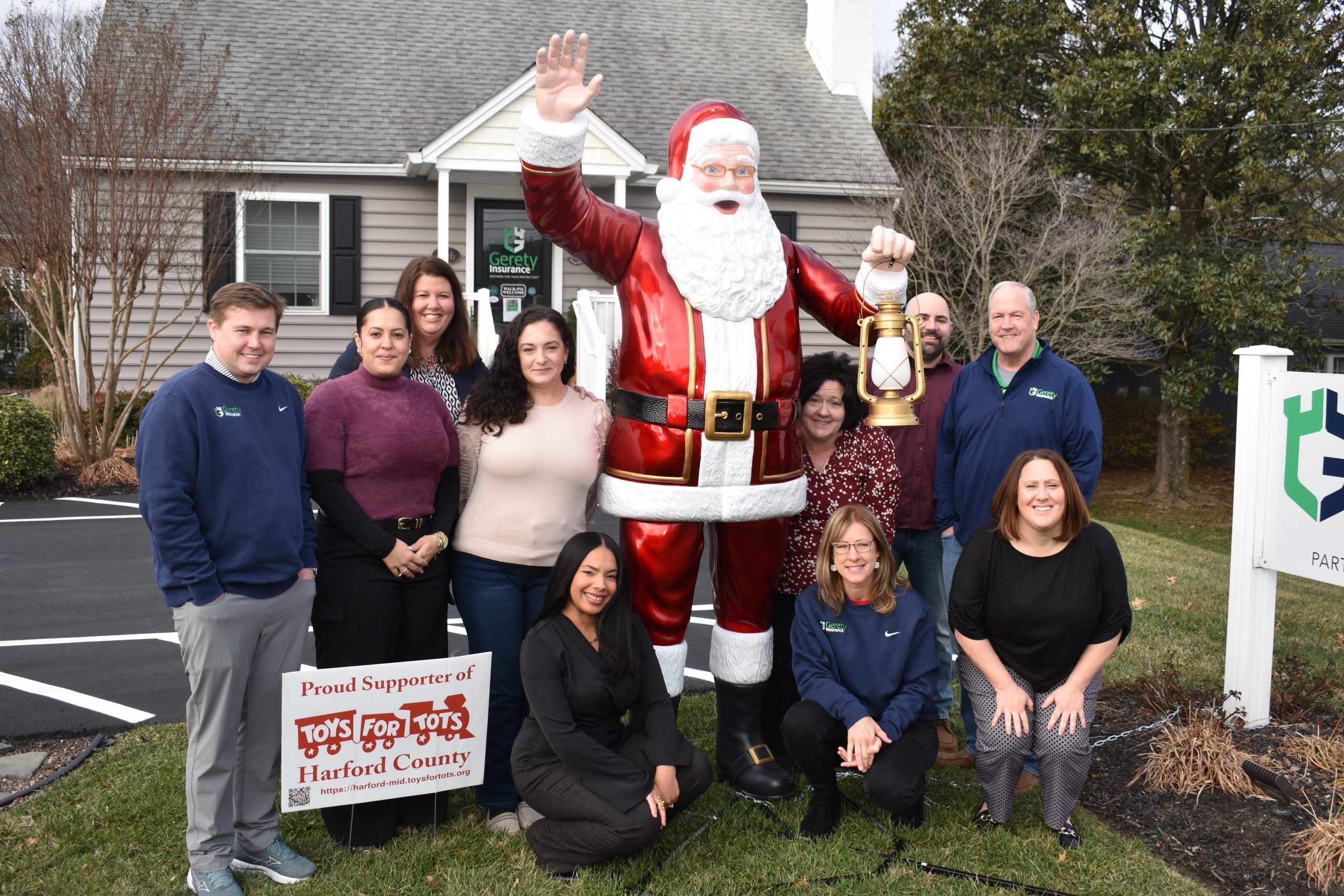 Group of Gerety coworkers posing with large Santa statue and Toys for Tots sign