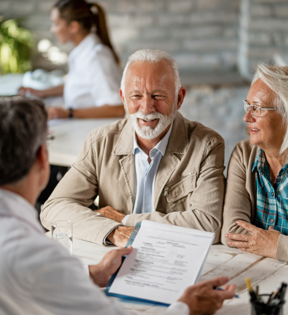 Elderly couple smiling while reviewing documents with an insurance agent