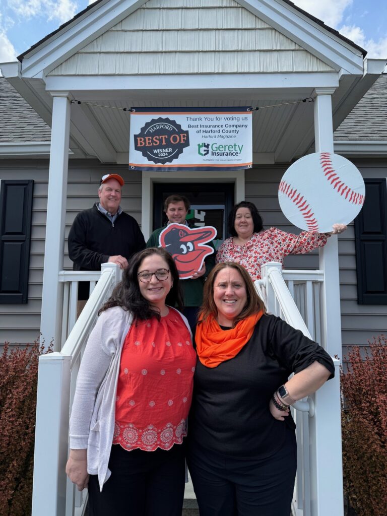 Five Gerety workers on a porch under a Best of Harford 2024 banner holding Orioles logo and baseball