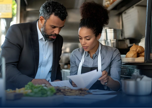 Restaurant workers reviewing papers inside a kitchen