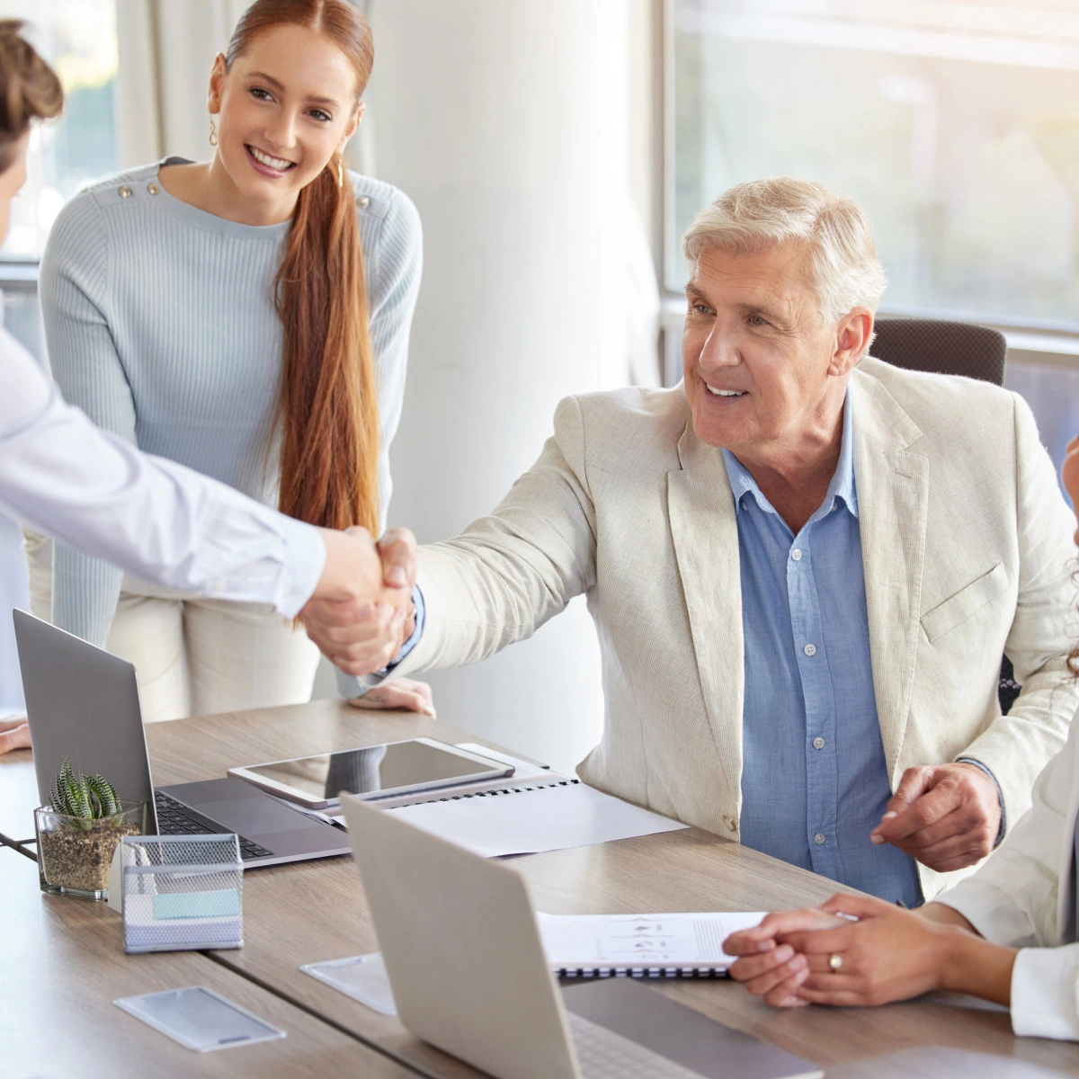 Smiling older man shaking hands with an insurance broker during a meeting