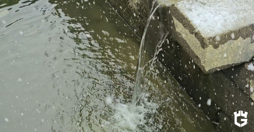 Floodwater spilling over a curb near a storm drain